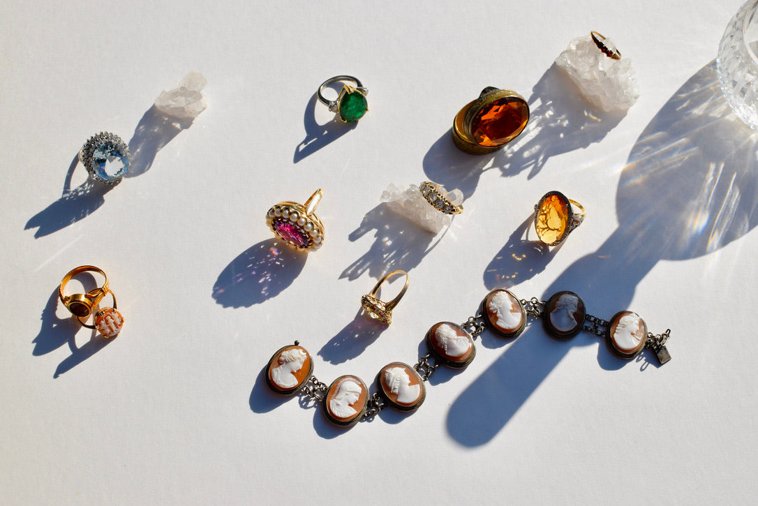 antique rings and jewelry are displayed with shadows against an off white background